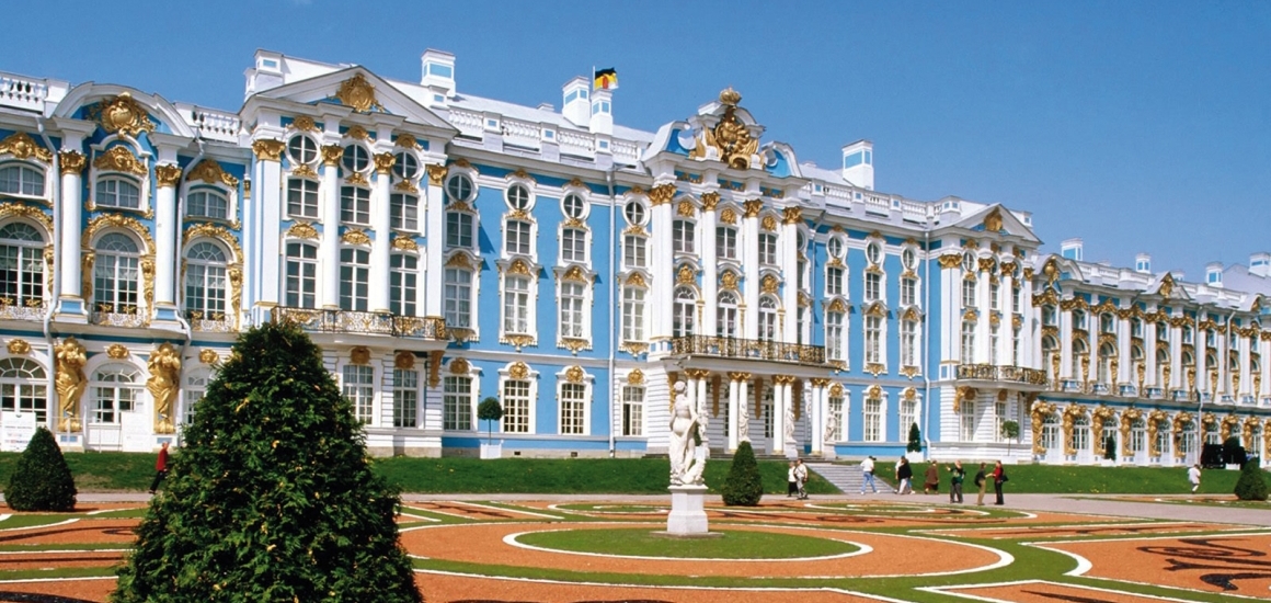 Das Bild zeigt den Katharinenpalast in Puschkin, nahe St. Petersburg, mit seiner barocken Architektur und den aufwendig gestalteten Gärten im Vordergrund.