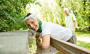 Ein älteres Paar das am Wasser Becken eine Kneipp Therapie macht