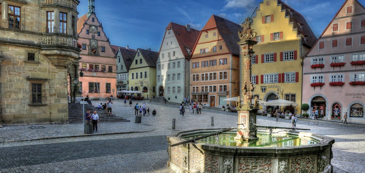 Marktplatz in Rothenburg ob der Tauber mit historischen Gebäuden und einem Brunnen im Vordergrund.