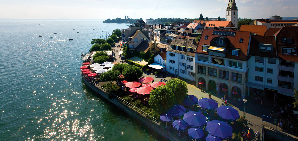 Luftaufnahme von Friedrichshafen am Bodensee mit Uferpromenade und Gebäuden.