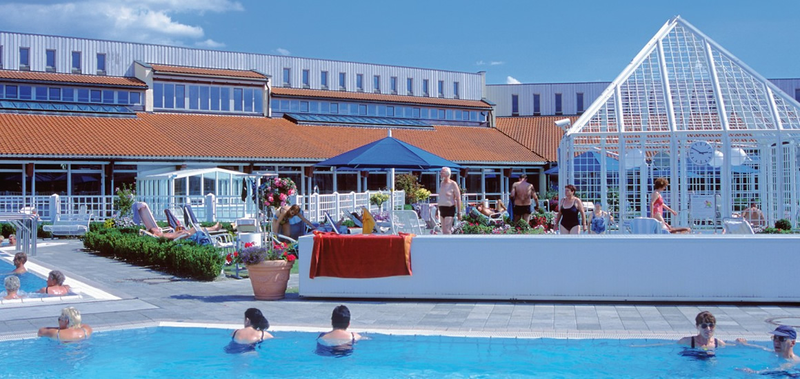 Außenansicht der Limes-Therme in Bad Gögging mit Pool und Menschen, die sich entspannen.