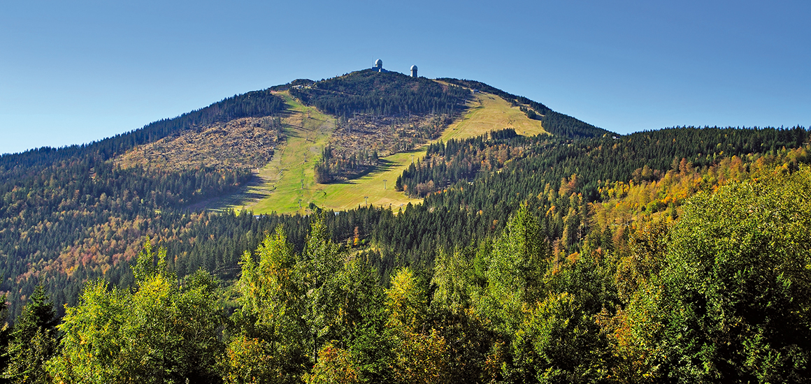 Blick auf den Großen Arber im Bayerischen Wald mit Skipisten und bewaldeten Hängen im Herbst.