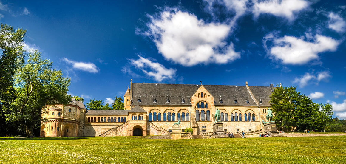 Kaiserpfalz in Goslar im Sommer mit blauem Himmel und grüner Wiese im Vordergrund.