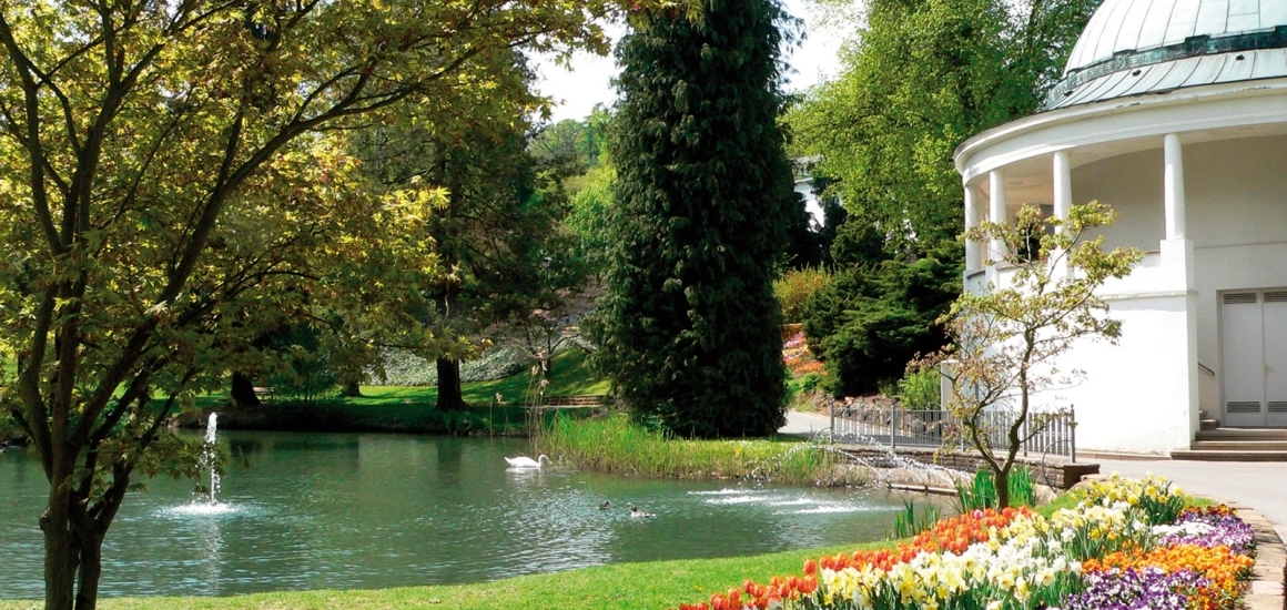 Kurpark in Bad Wildungen mit Teich, Springbrunnen, Blumenbeet und Pavillon.