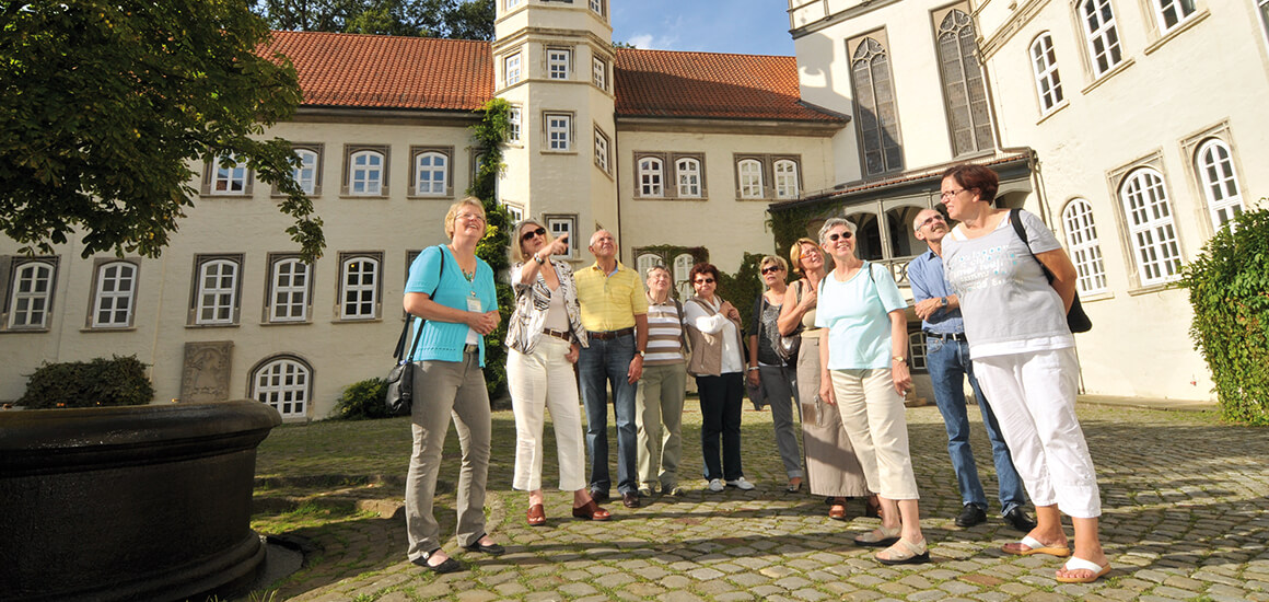 Eine Gruppe von Menschen steht im Schlosshof von Gifhorn, umgeben von historischen Gebäuden.