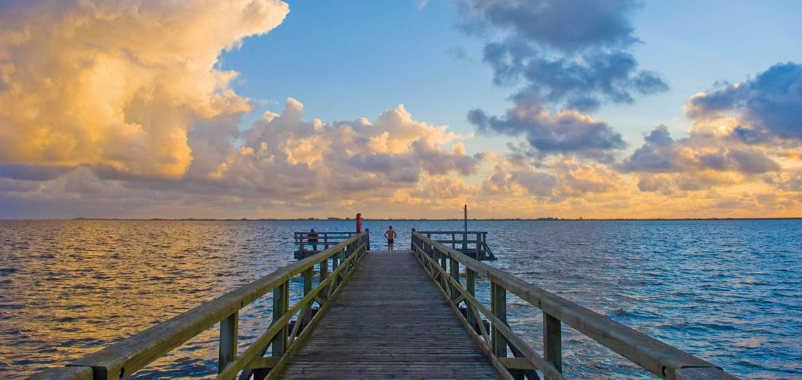 Seebrücke in Husum bei Sonnenuntergang mit Wolken am Himmel