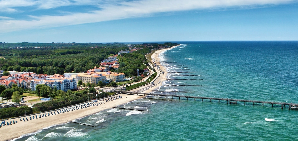Luftaufnahme von Kühlungsborn an der Ostsee mit Strand, Meer und Gebäuden im Hintergrund.