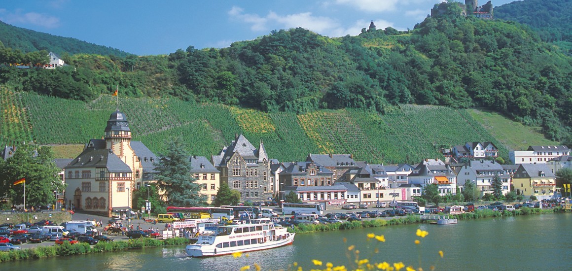 Panoramablick auf Bernkastel-Kues mit dem Fluss, Weinbergen und einer Burg im Hintergrund