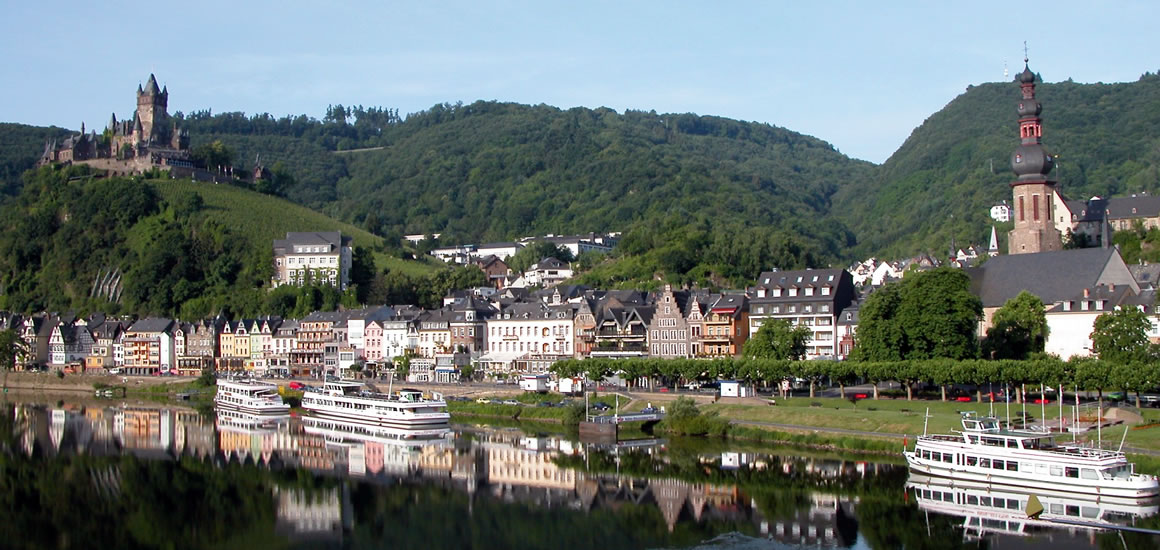 Panorama von Cochem an der Mosel mit der Reichsburg auf einem Hügel und der Stadt im Vordergrund, einschließlich der Mosel mit Booten.