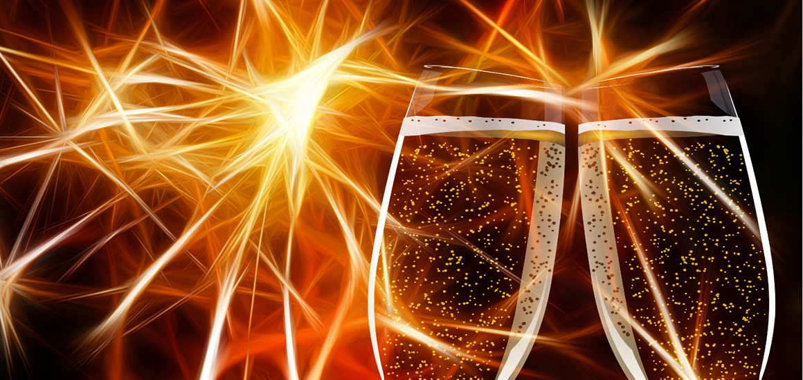 Zwei mit Sekt gefüllte Gläser vor einem Hintergrund mit Feuerwerks- oder Lichtstrahlen.
