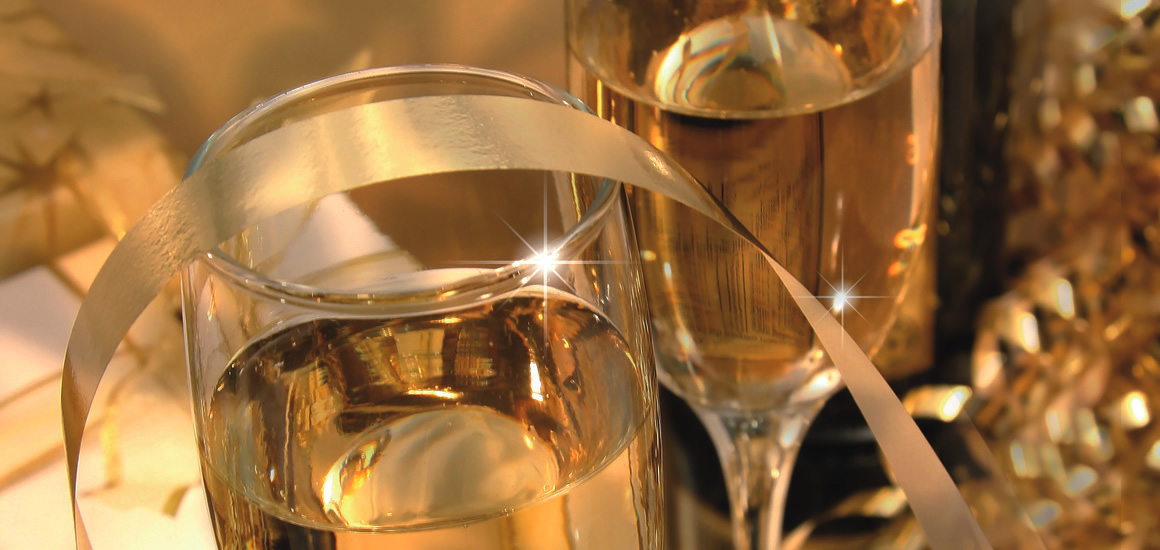 Zwei Gläser mit Sekt und goldenen Dekorationen, die eine festliche Silvesteratmosphäre darstellen.
