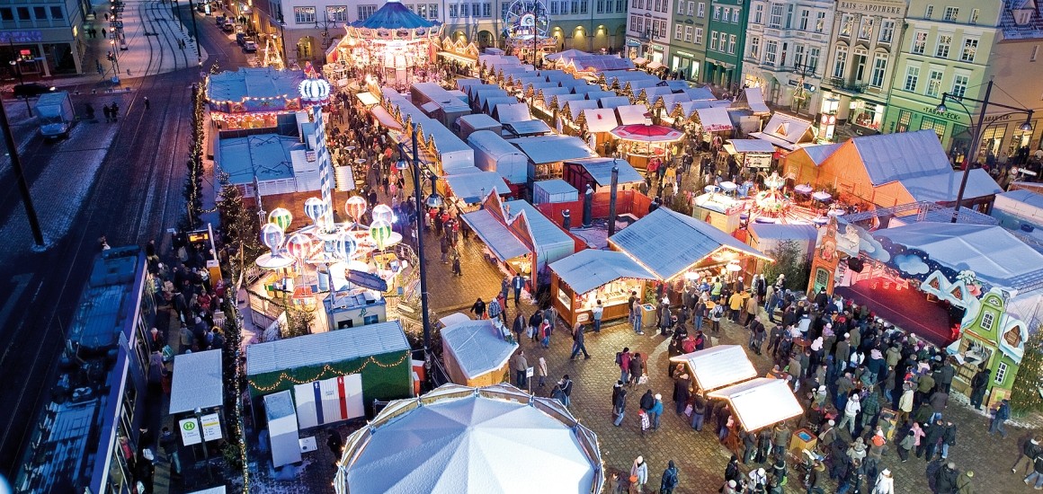 Luftaufnahme eines Weihnachtsmarkts in Deutschland mit zahlreichen Ständen und Menschen.