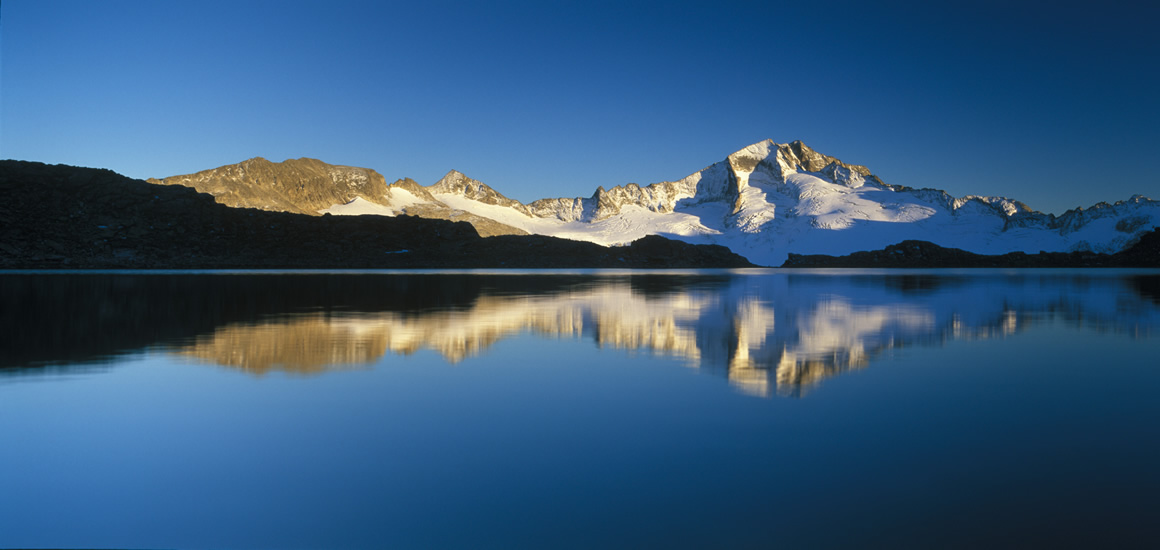 Berglandschaft mit schneebedecktem Gipfel und Spiegelung im ruhigen See, vermutlich die Hochalmspitze in Kärnten, Österreich.