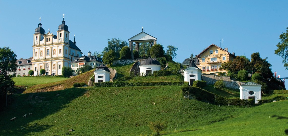 Ansicht der Wallfahrtskirche Maria Plain mit umliegenden Gebäuden und Kapellen auf einem Hügel in Oberösterreich.