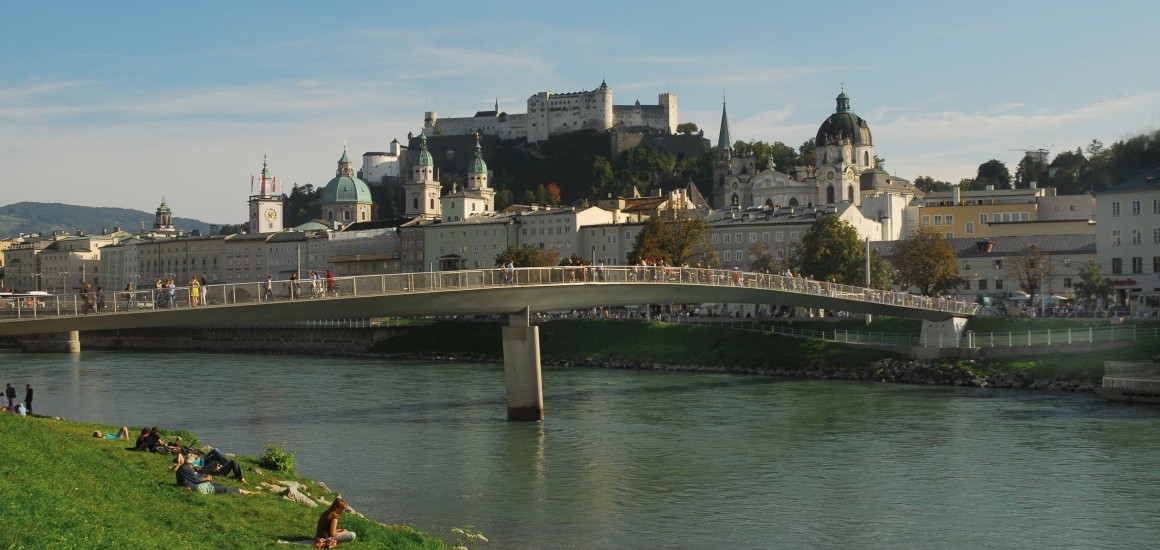 Blick auf die Salzachbrücke mit der Stadt Salzburg im Hintergrund, einschließlich der Festung Hohensalzburg und der Salzburger Altstadt.