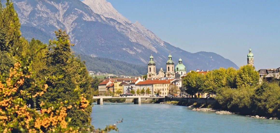 Blick auf Innsbruck mit dem Inn im Vordergrund und den Alpen im Hintergrund.