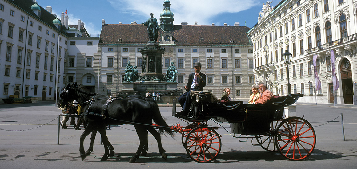 Pferdekutsche auf einem Platz in Wien mit historischen Gebäuden im Hintergrund.