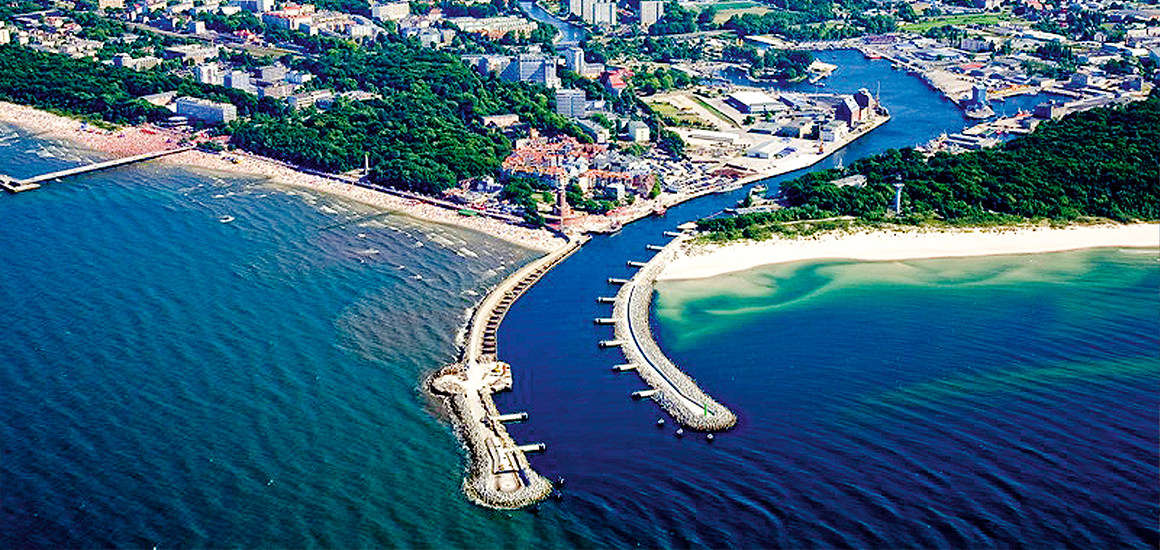 Luftaufnahme einer Küstenstadt mit Hafen und Stränden, vermutlich Kolberg in Polen.