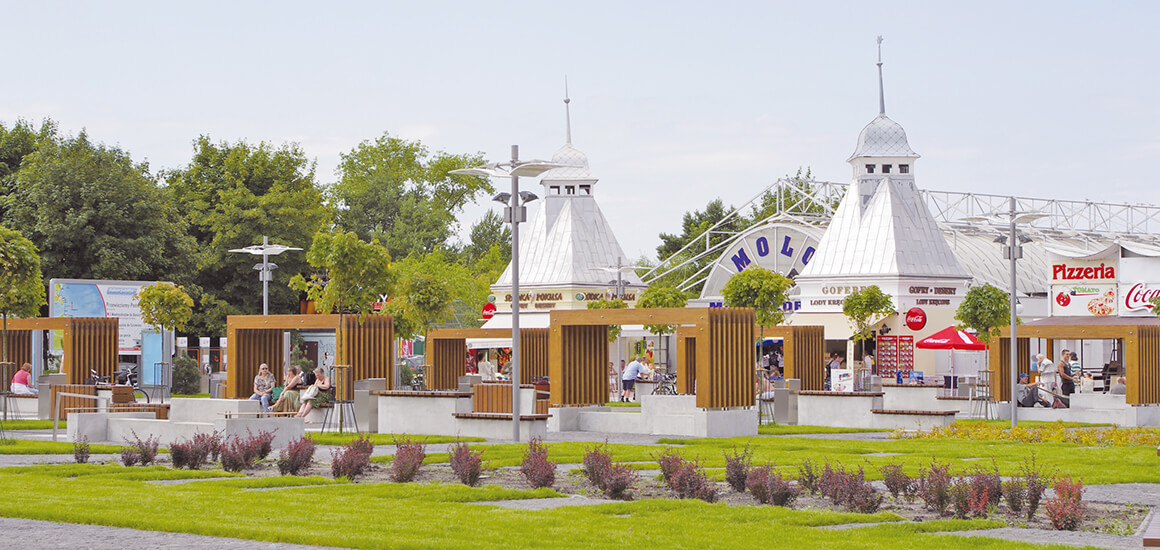 Promenade in Misdroy mit Pavillons, Bäumen und Menschen, die die Umgebung genießen.