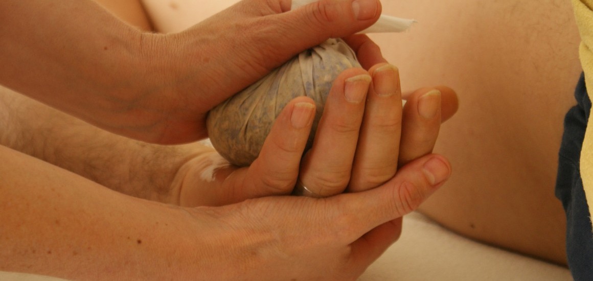 Nahaufnahme einer Massage mit Kräuterstempel auf einer Hand