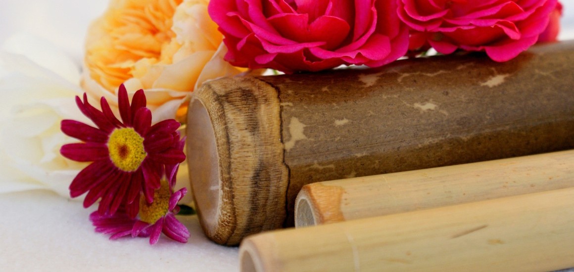 Nahaufnahme von Blumen und Bambusstäben, die eine entspannende Wellness-Atmosphäre vermitteln.