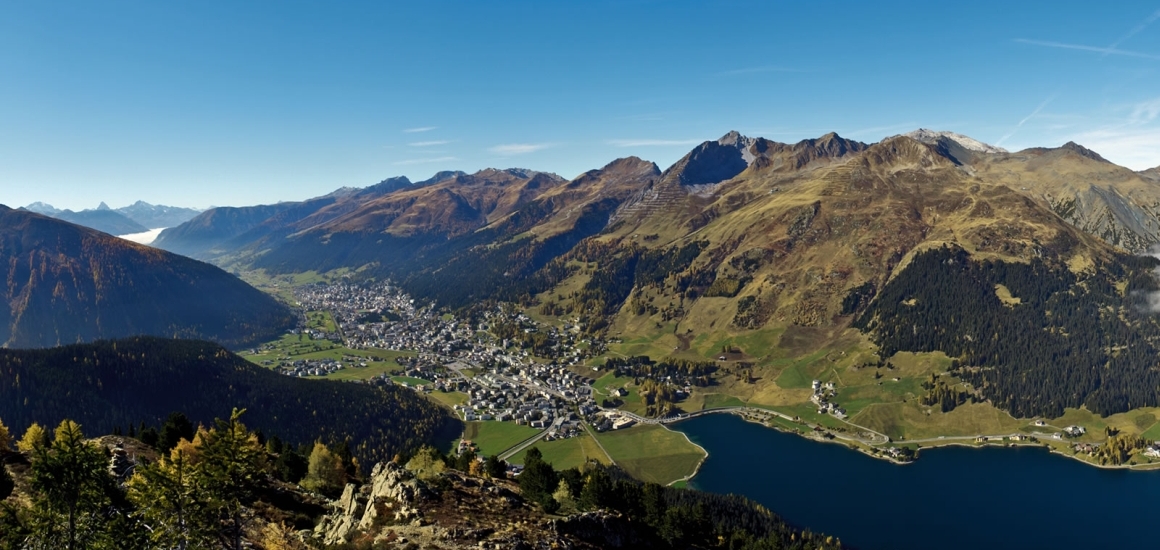 Panoramablick auf Davos, Schweiz, mit Bergen im Hintergrund und einem See im Vordergrund.